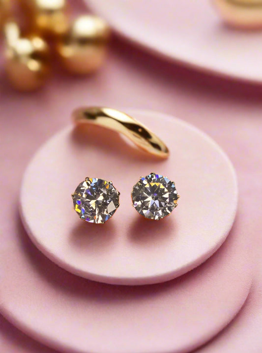 Diamond stud earrings held between fingers with 'GRA' branding in the background